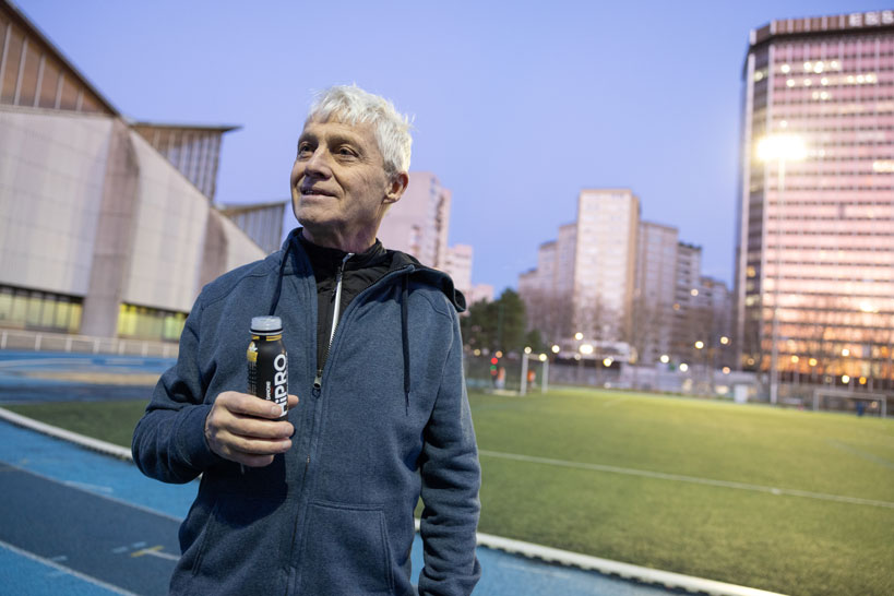 Een man houdt een recyclebare verpakking vast van HiPRO op een sportveld