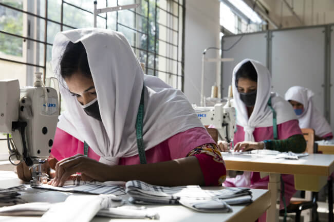 vrouw met witte hoofddoek achter naaimachine