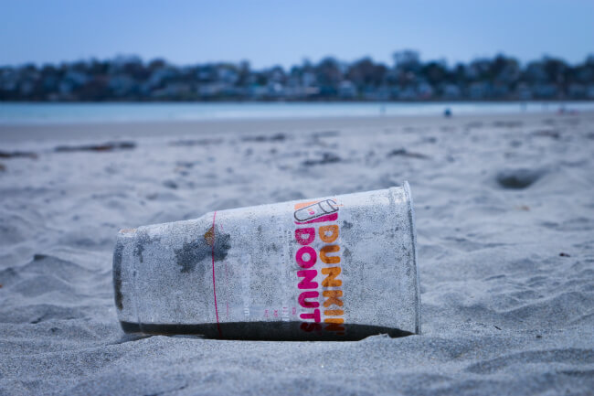 Plastic beker die is aangespoeld op het strand