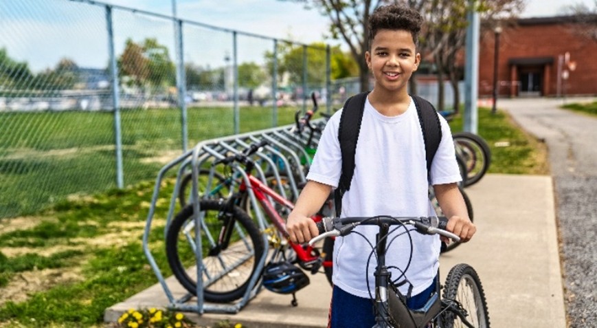 Een kind met een fiets bij een fietsenrek    