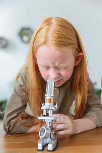 Meisje kijkt door een microscoop.