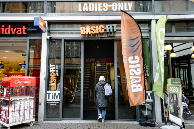 vrouw loopt filiaal van basic fit binnen